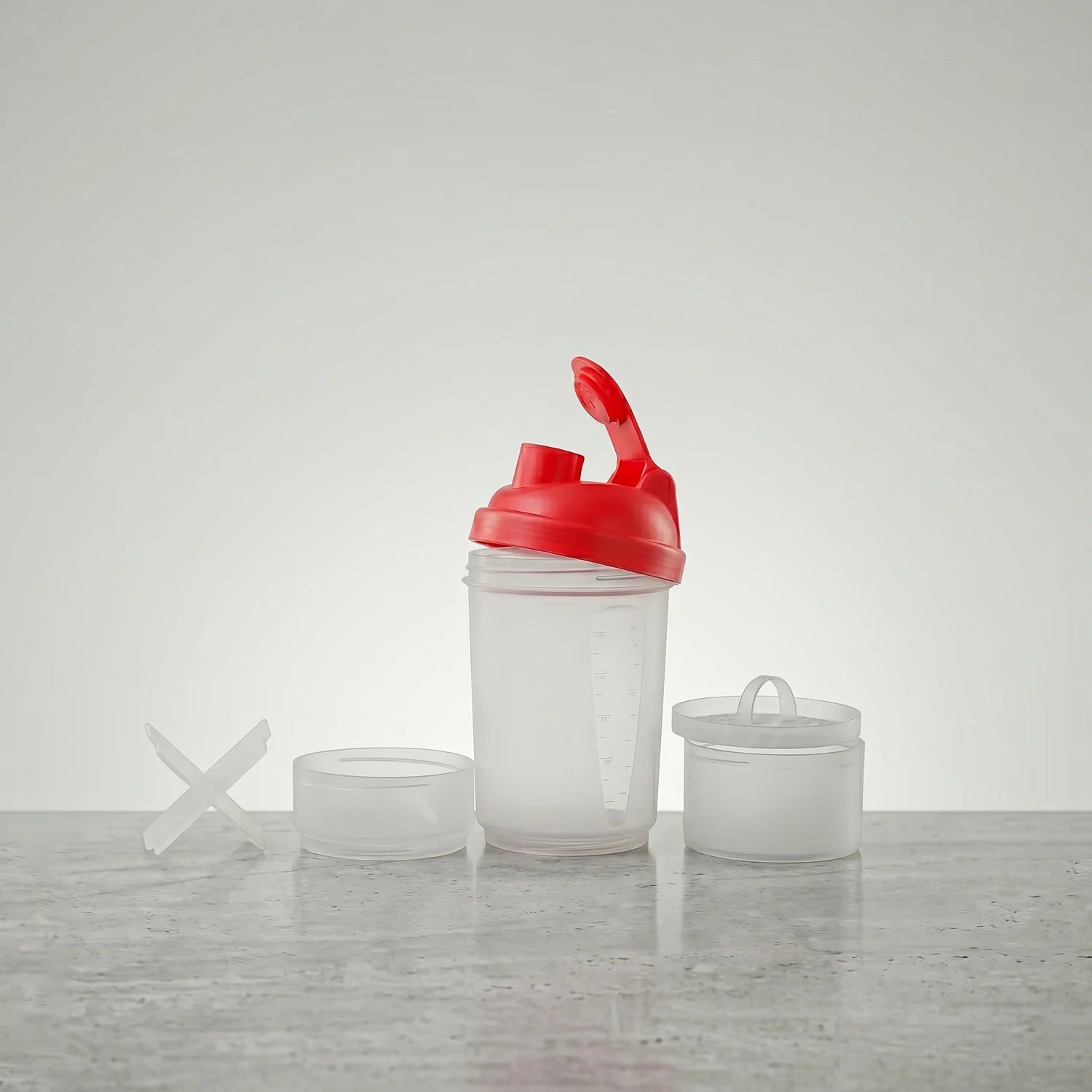 Clear shaker bottle with red lid on a gray surface